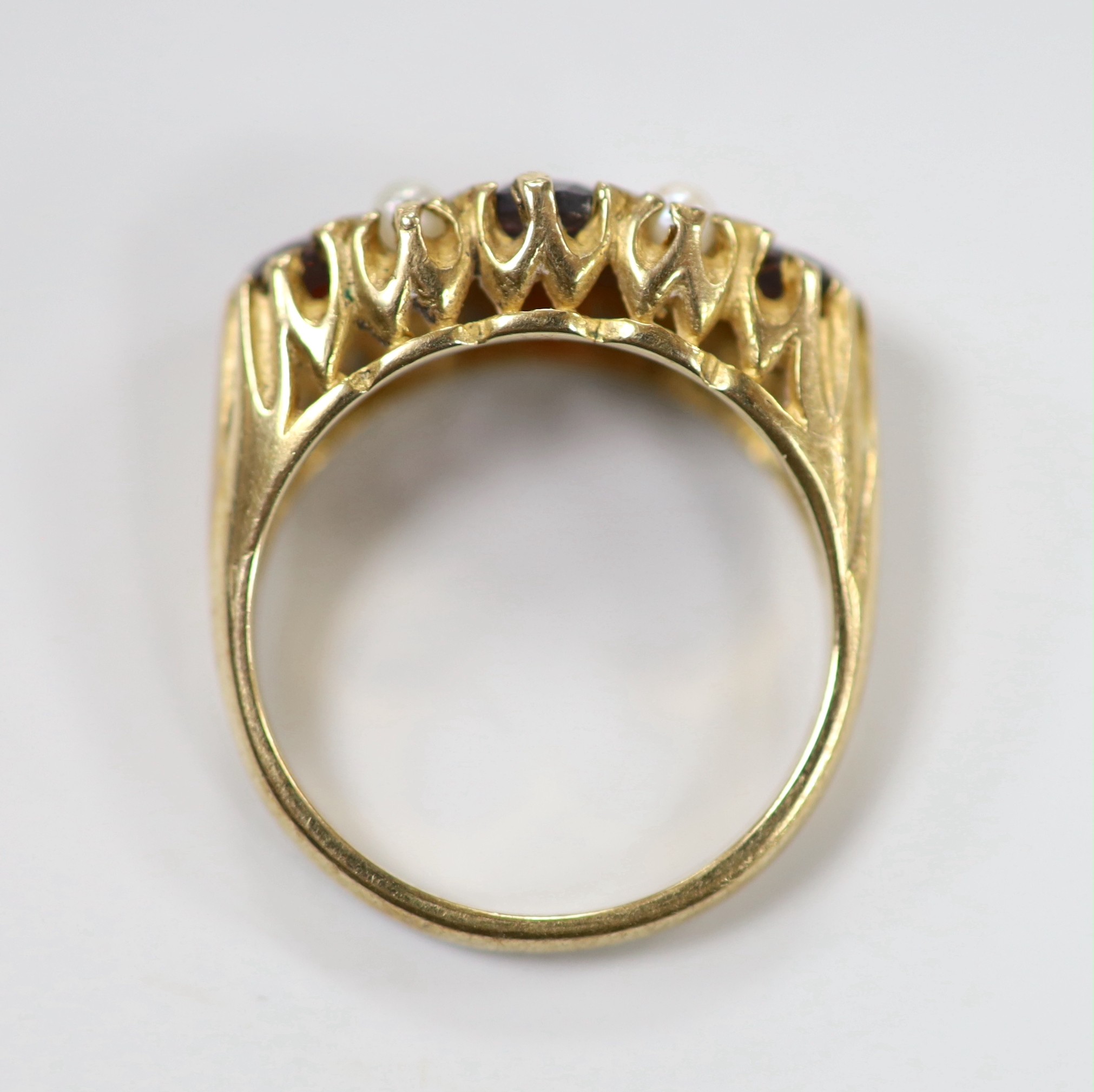 A 1970's 9ct gold, three stone garnet and four stone split pearl set half hoop ring, size K/L, gross weight 3.6 grams.